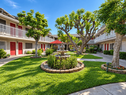 A courtyard with a fountain surrounded by trees and apartment buildings.
