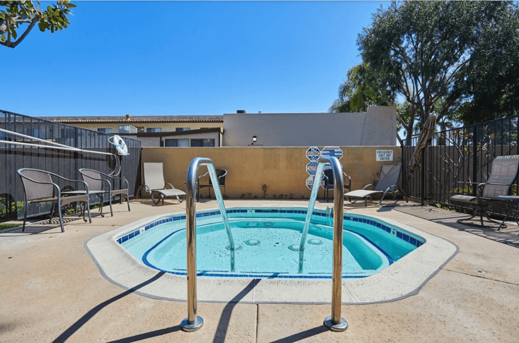 our resort style hot tub is next to our patio with chairs and a fence at Huntington Terrace North Senior, Huntington Beach California