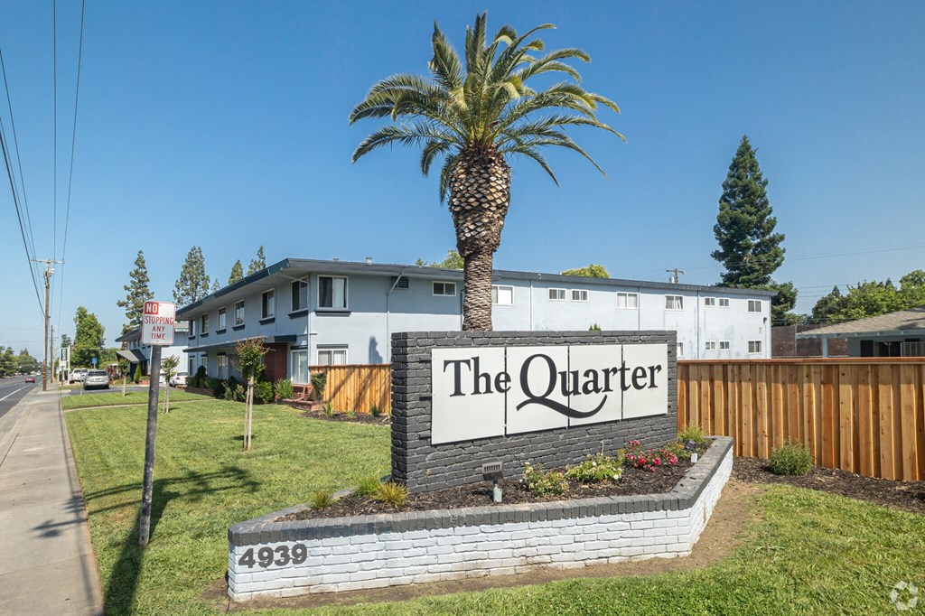 A sign that says "The Quarter" is in front of a building with a palm tree.