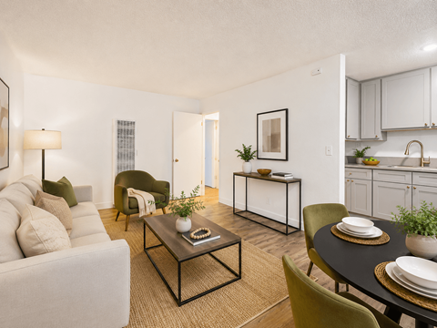 A living room with a white couch, a coffee table, and a dining table set for two.