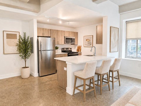 A kitchen with a white countertop and wooden bar stools.