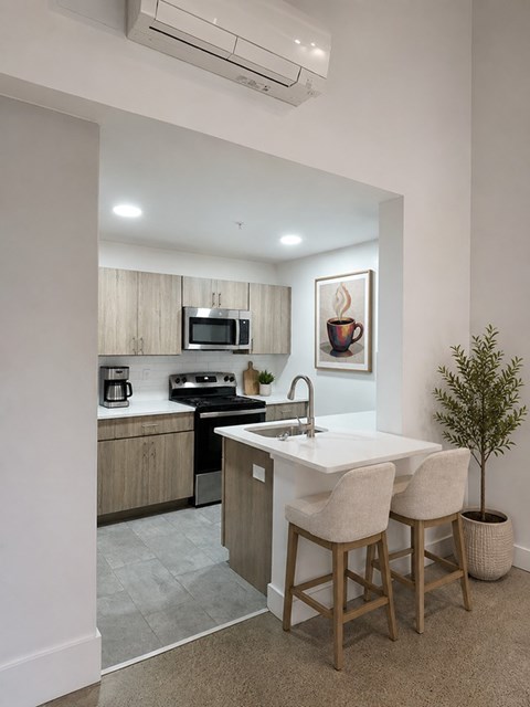A kitchen with a white countertop and wooden bar stools.
