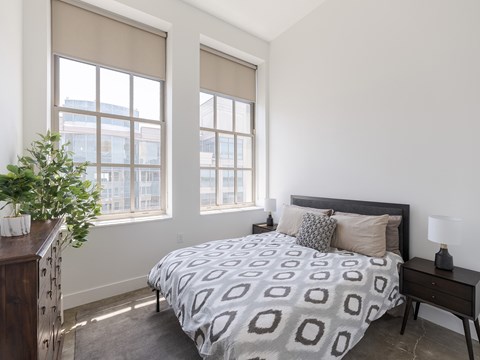 Bright bedroom with industrial windows and roller shades at The Bell Apartments, Trenton, NJ
