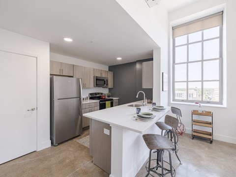 A kitchen with a white island and bar stools.