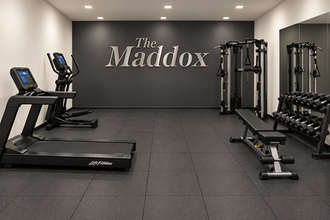 A gym with a treadmill, weights, and a wall that says The Maddox.