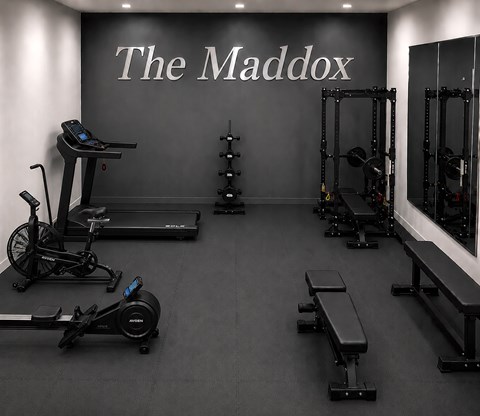 A gym with a variety of equipment including treadmills, rowing machines, and weight racks.