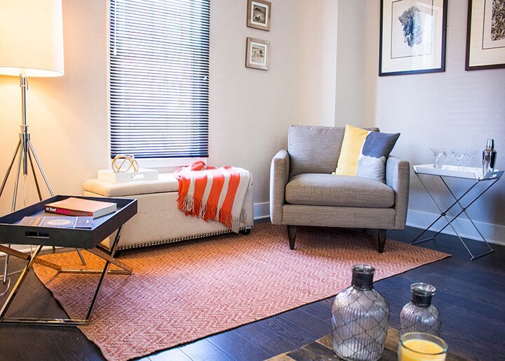 A living room with a grey couch, a coffee table, and a lamp.