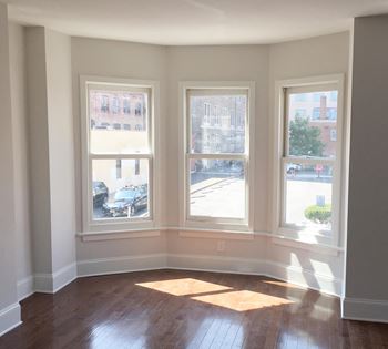 A room with three windows and wooden floors.