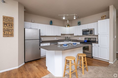 A kitchen with white cabinets and a wooden island.