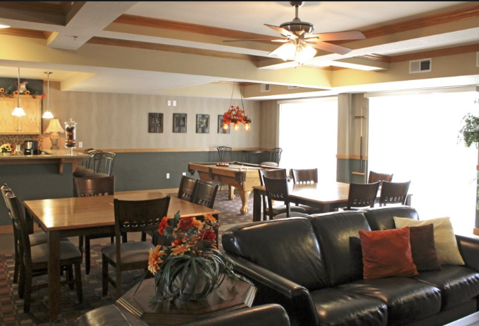 a large community room with leather couches and a dining room table with chairs