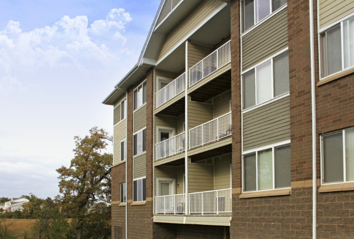 an apartment building with balconies and trees in the background
