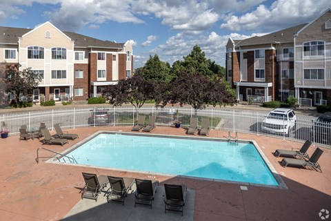 Swimming pool with lounge chairs and white fence at Hearthstone and Townhomes Apartments, Apple Valley, Minnesota