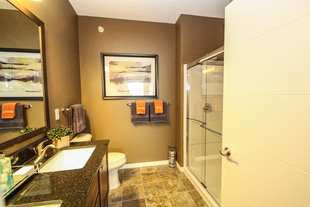 a bathroom with a toilet a sink and a shower at The Flats at Cedar Grove, Eagan, MN
