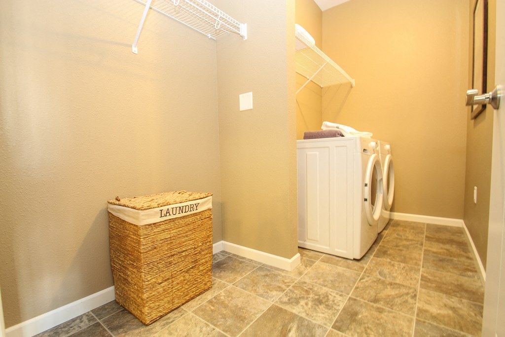 a laundry room with a large basket and a washer and dryer at The Flats at Cedar Grove, Eagan, Minnesota