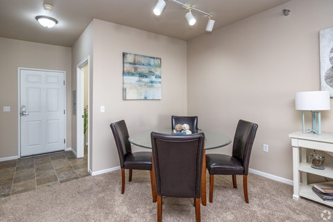 Dining area with glass table and upholstered chairs at Hearthstone and Townhomes Apartments, Apple Valley, Minnesota