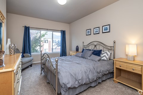 Bedroom with metal bed frame and wood furnishings at Hearthstone and Townhomes Apartments, Apple Valley, MN 55124
