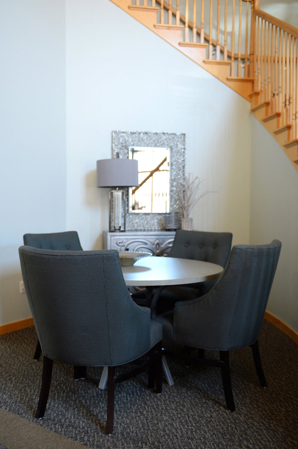 a round table with four chairs and a lamp in a room with a staircase in the background at Hearthstone Apartments and Townhomes, Apple Valley