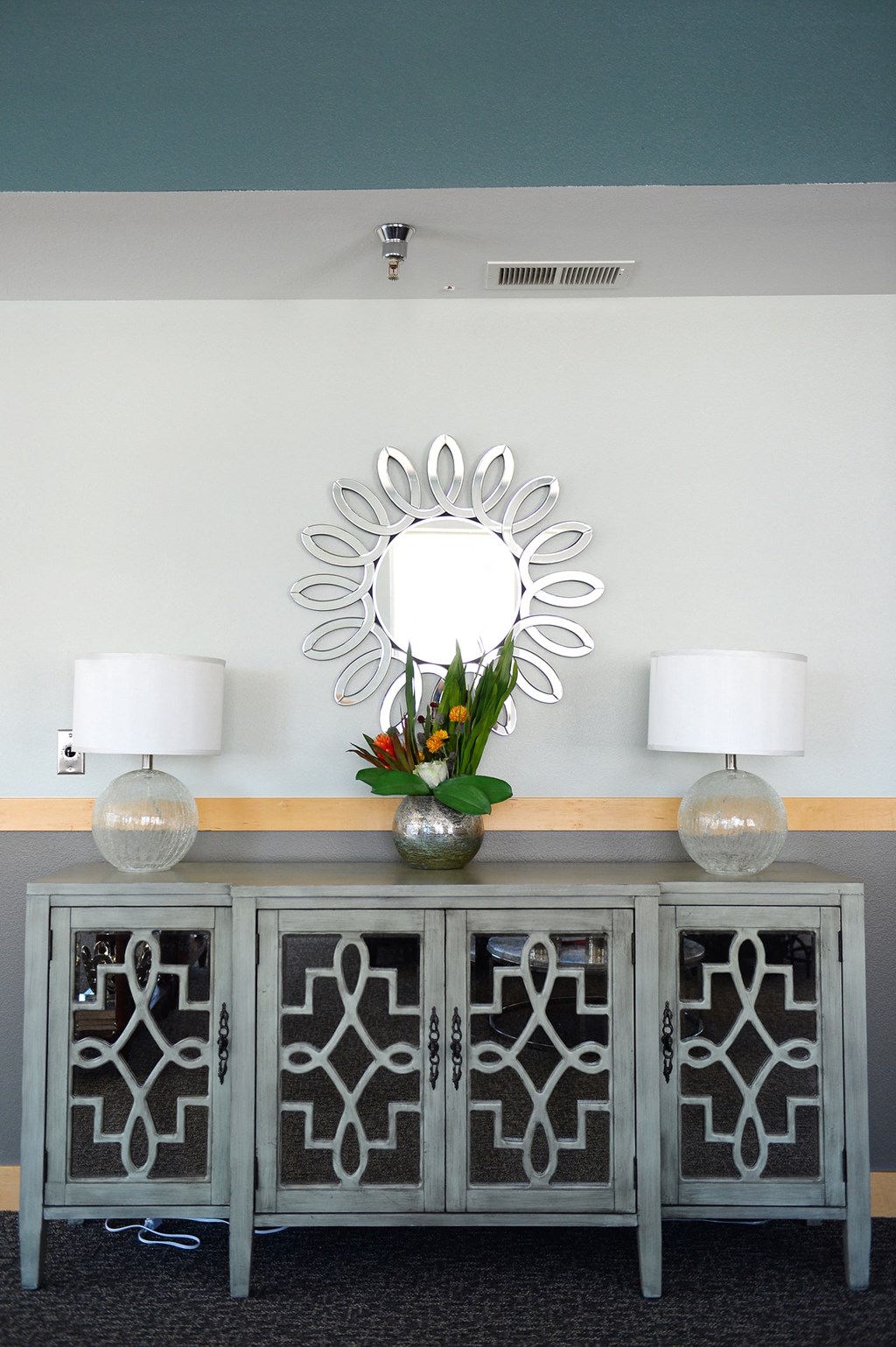 a console table with two lamps and a mirror on the wall at Hearthstone Apartments and Townhomes, Minnesota