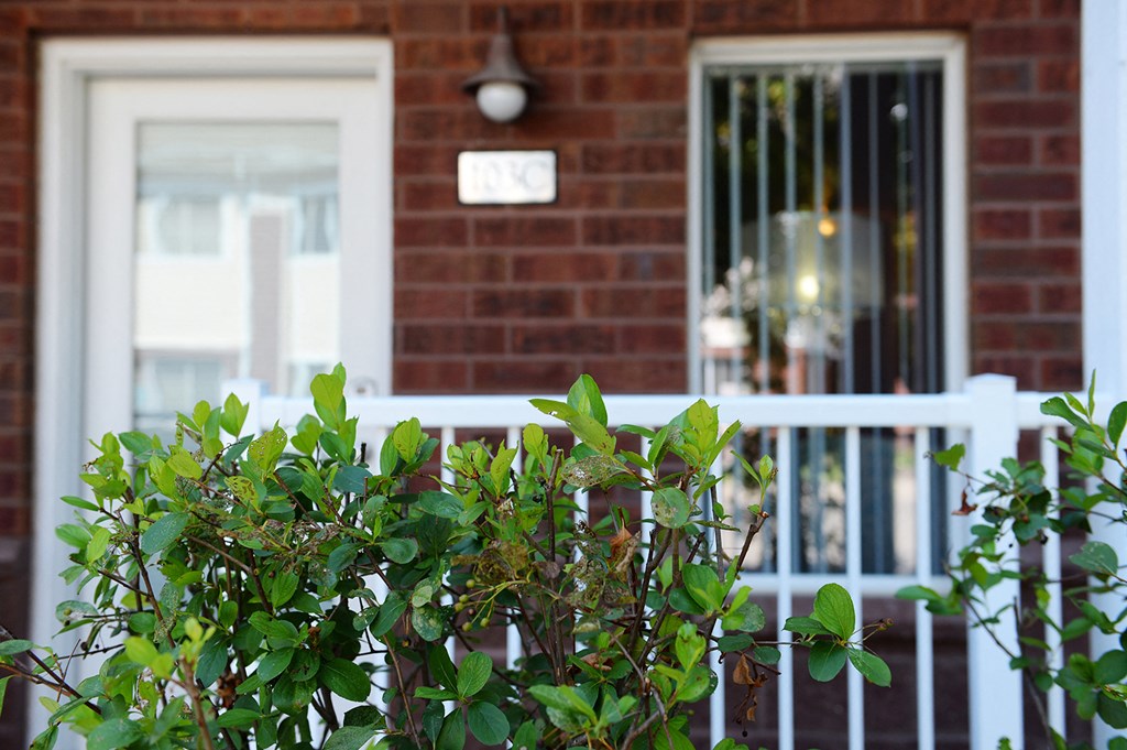 a red brick house with a white fence in front of it at Hearthstone Apartments and Townhomes, Minnesota