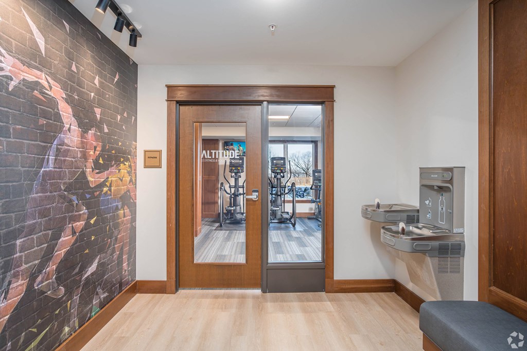 a gym with a treadmill and a door to a room with a sink and a