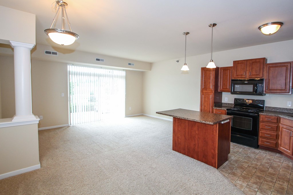 a kitchen with an island and a living room in the background