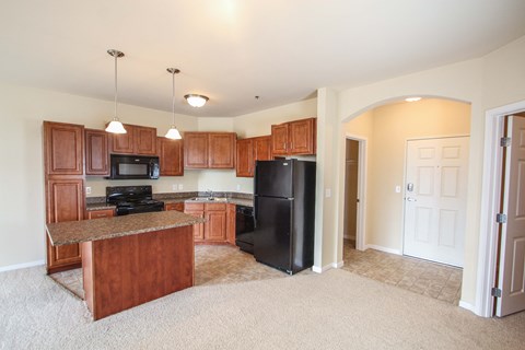 a kitchen with wooden cabinets and a black refrigerator