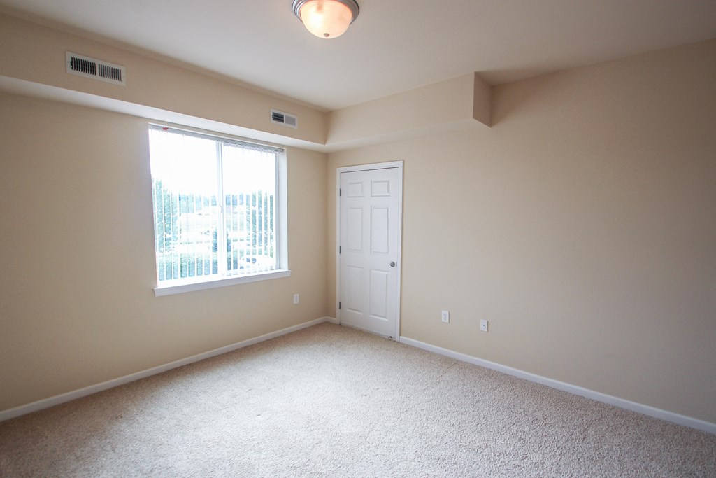 a bedroom with a large window and beige walls
