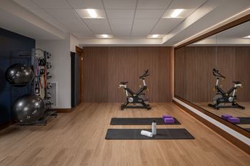 A gym with a mirror, exercise bikes, and a large ball.