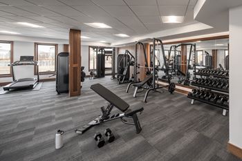 A gym with a variety of equipment including weights and a bench.