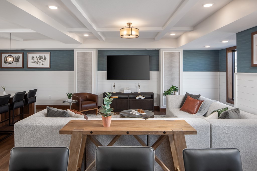 A modern living room with a grey couch, a wooden table, and a flat screen TV.