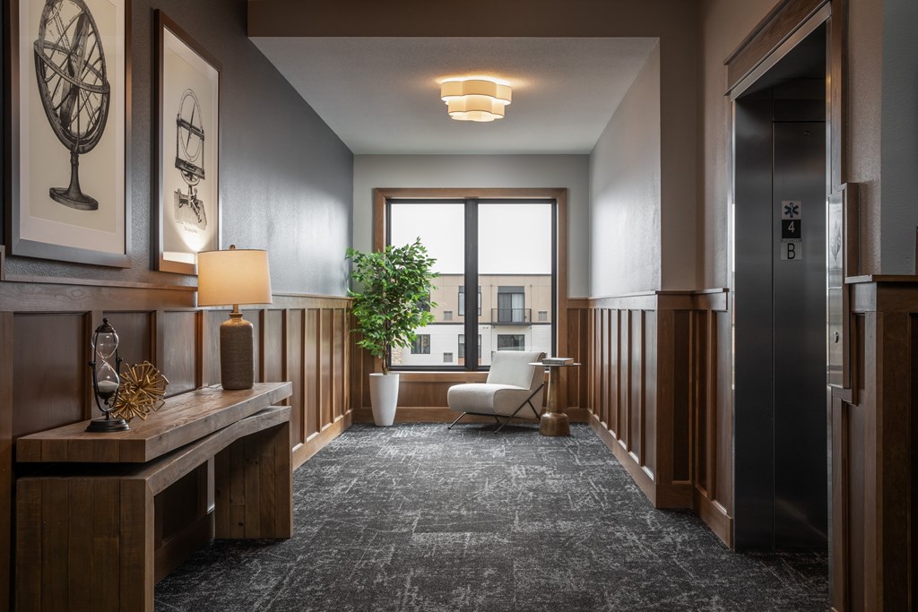 A hallway with a bench, a potted plant, and a window.