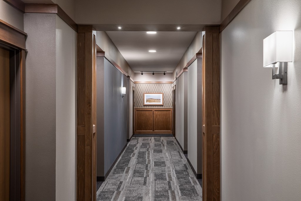 A long hallway with a carpeted floor and wooden doors on either side.