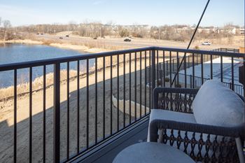 A balcony with a chair and a table overlooking a body of water.