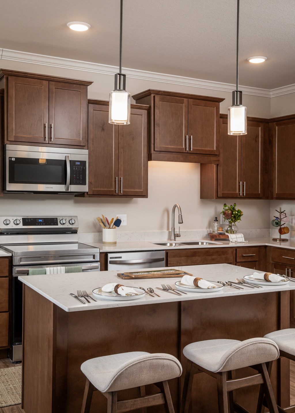 A kitchen with brown cabinets and a white island with two chairs.