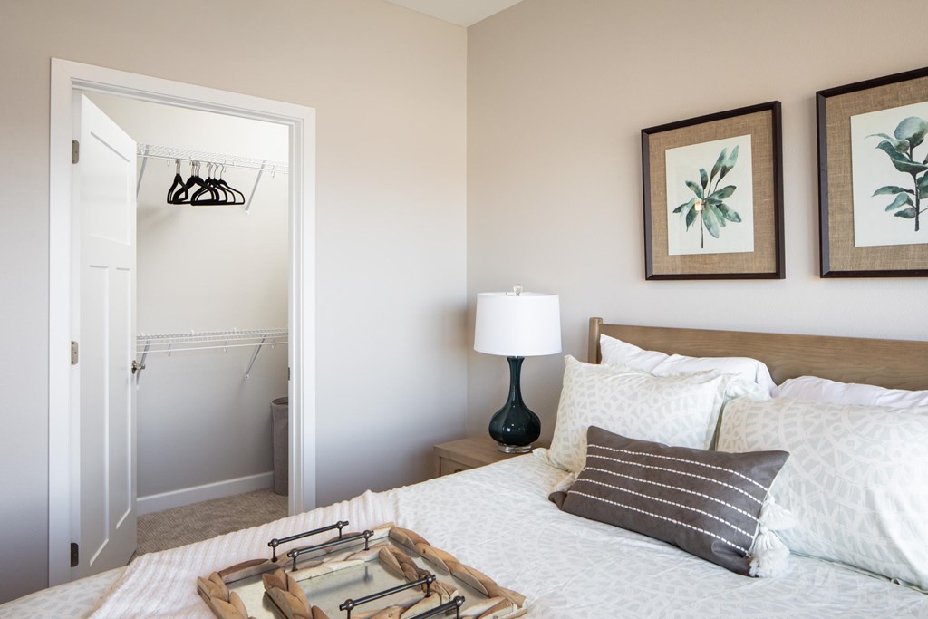 A bedroom with a bed, pillows, a lamp, and a picture on the wall.