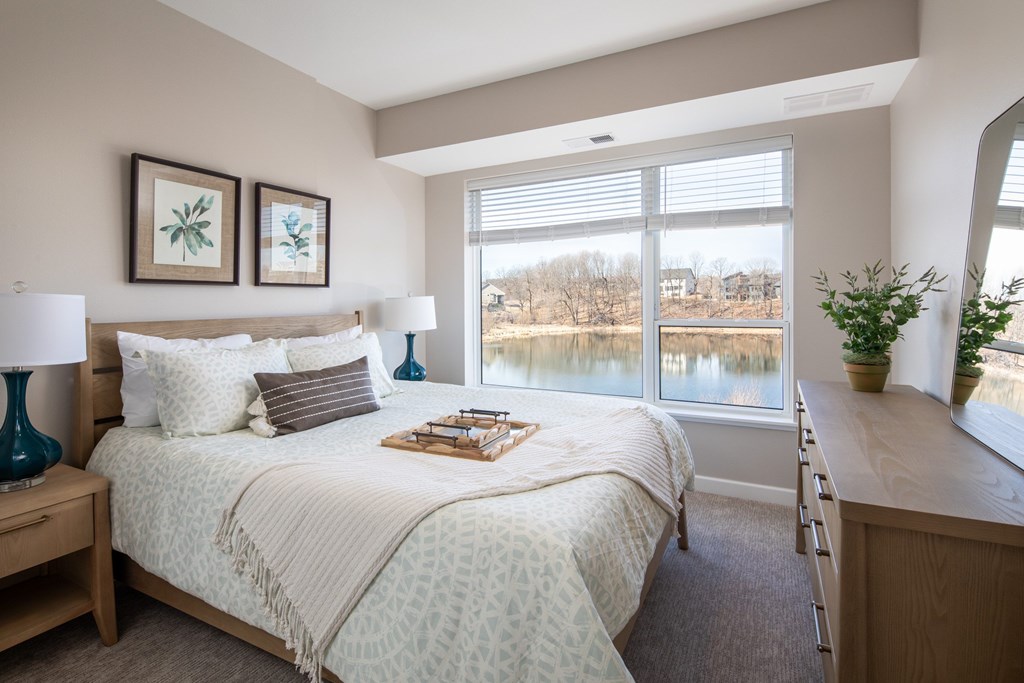 A bedroom with a large bed and a view of a lake through the window.