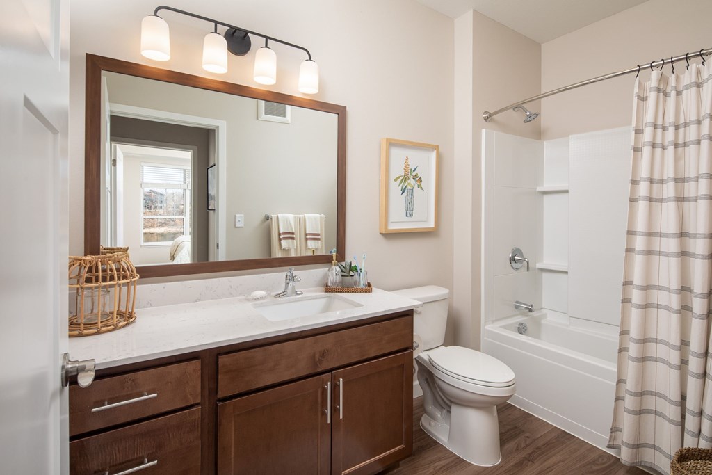 A bathroom with a white toilet, a sink with a mirror above it, and a shower with a curtain.