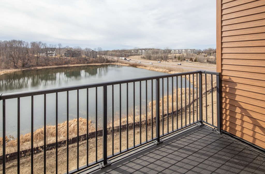 A balcony with a black railing overlooks a body of water.