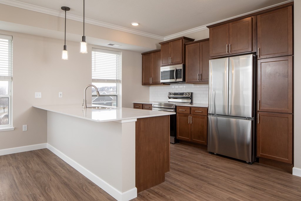 A kitchen with a refrigerator, microwave, and cabinets.