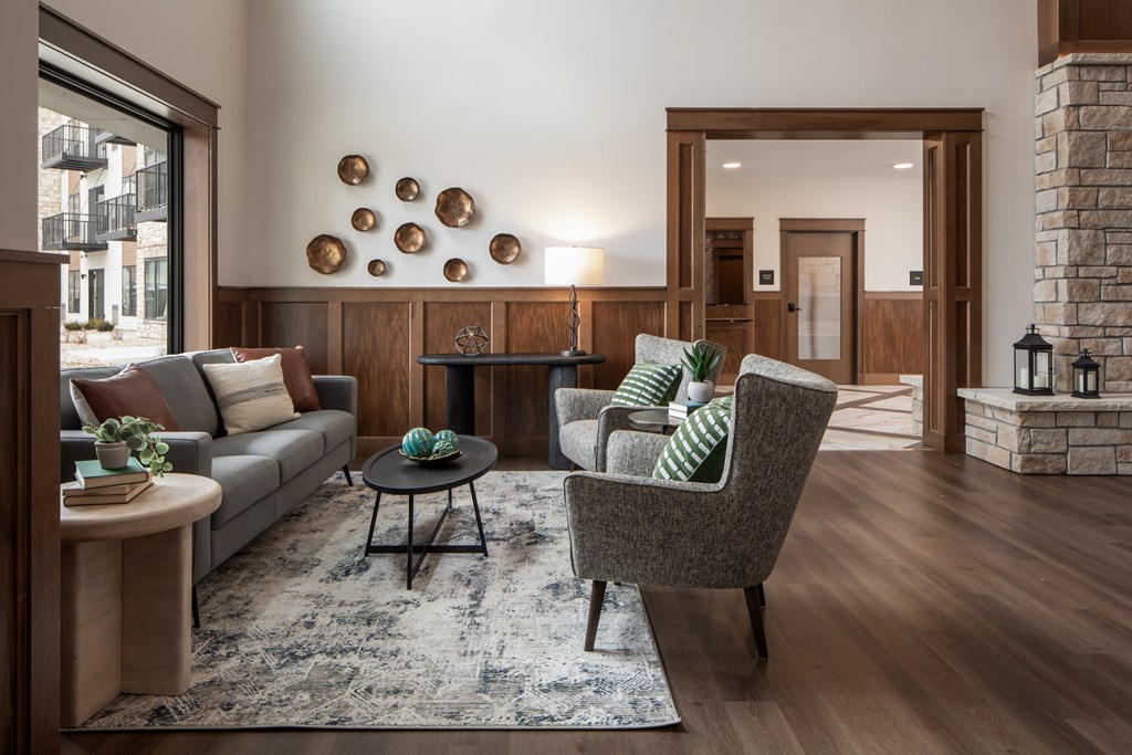 A living room with a grey sofa, a black coffee table, a grey armchair, and a fireplace.