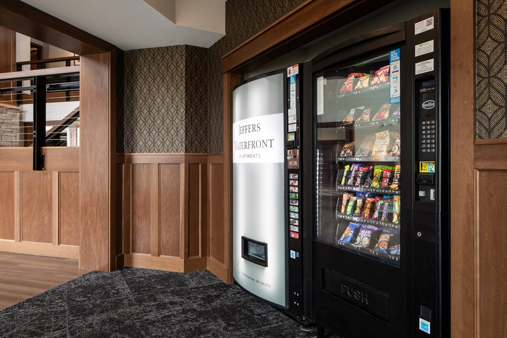 A modern vending machine is placed in a room with wooden walls.
