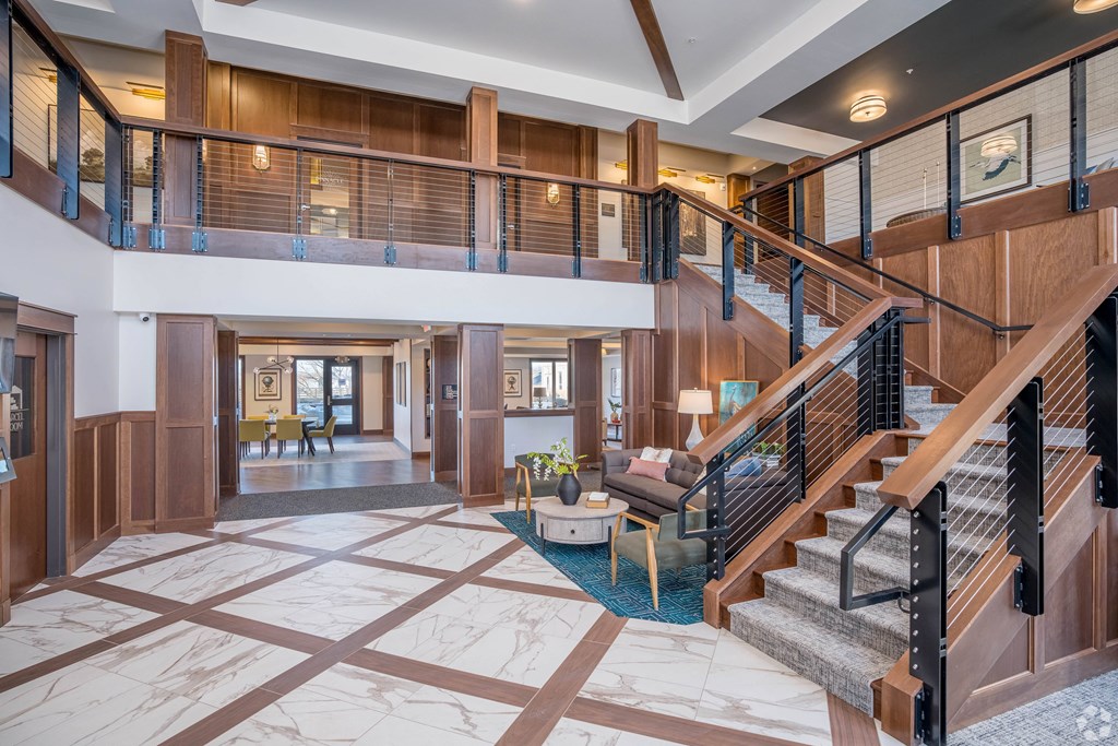 the lobby of a hotel with a staircase and a living room