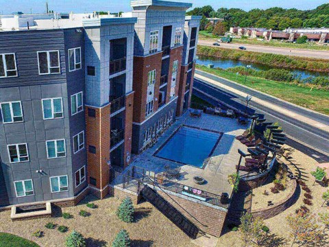 an aerial view of a building with a pool in front of it at The Flats at Cedar Grove, Eagan