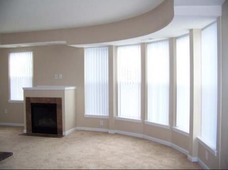 an empty living room with a fireplace and large windows