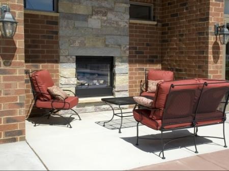 a patio with red chairs and a fireplace