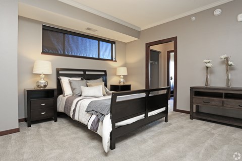 A bedroom with a large bed, two nightstands, and a window.