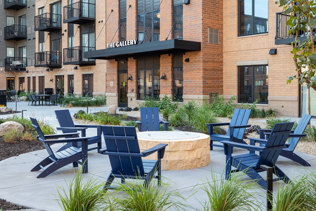 a firepit with adirondack chairs in front of a building at The Gallery Apartments, Minnesota