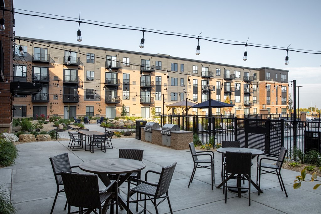 an outdoor patio with tables chairs and grills at The Gallery Apartments, Burnsville