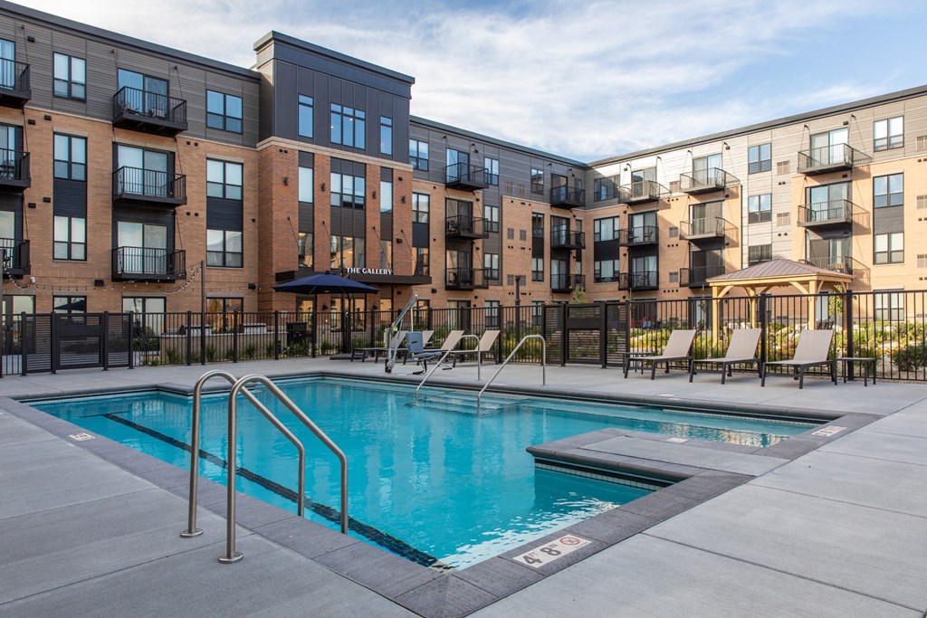 a swimming pool with chaise lounge chairs and a gazebo in front at The Gallery Apartments, Burnsville, MN, 55337