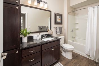a bathroom with dark cabinets and a white bathtubat The Carver Apartments, Chaska